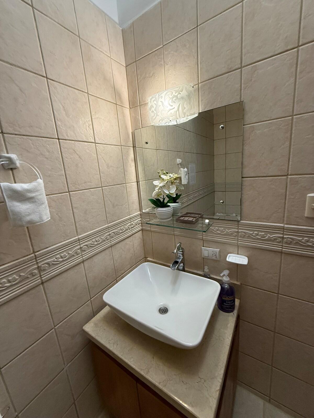 Bathroom with a white vessel sink, mirror, and warm tile