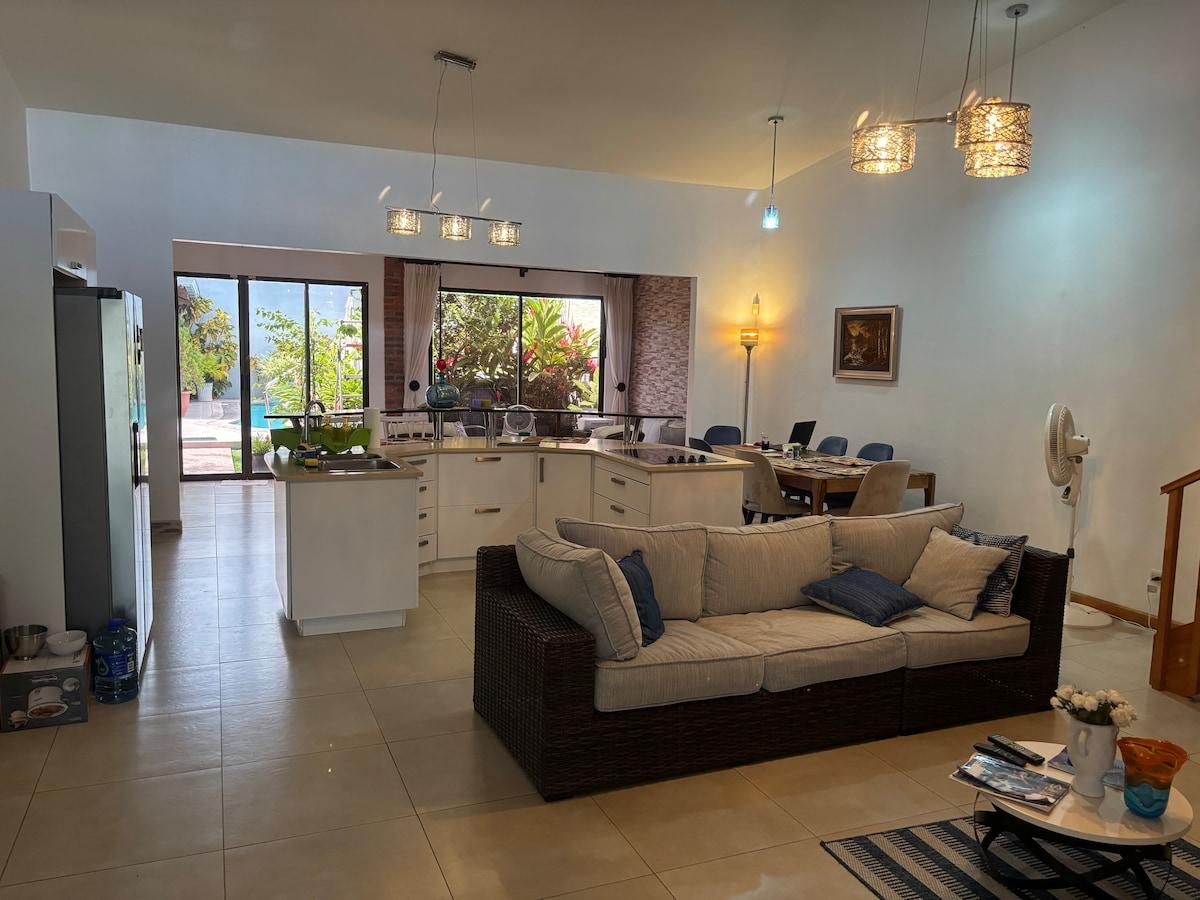 Open living room, dining table, and white kitchen looking toward the pool