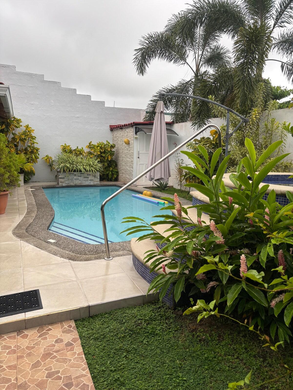 Private pool and garden at Casa Jannat, with a stair rail, palms, and flowering plants