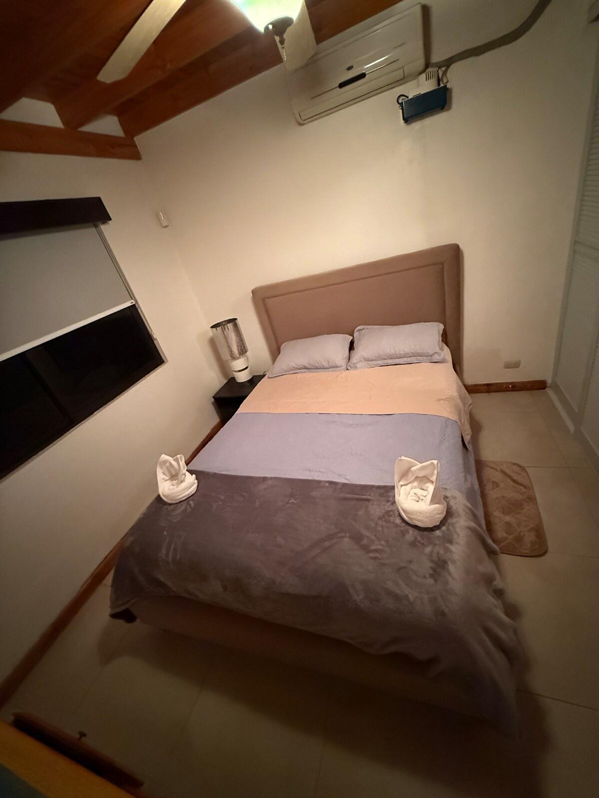 Queen bedroom with its own air conditioner and a wood-beamed ceiling