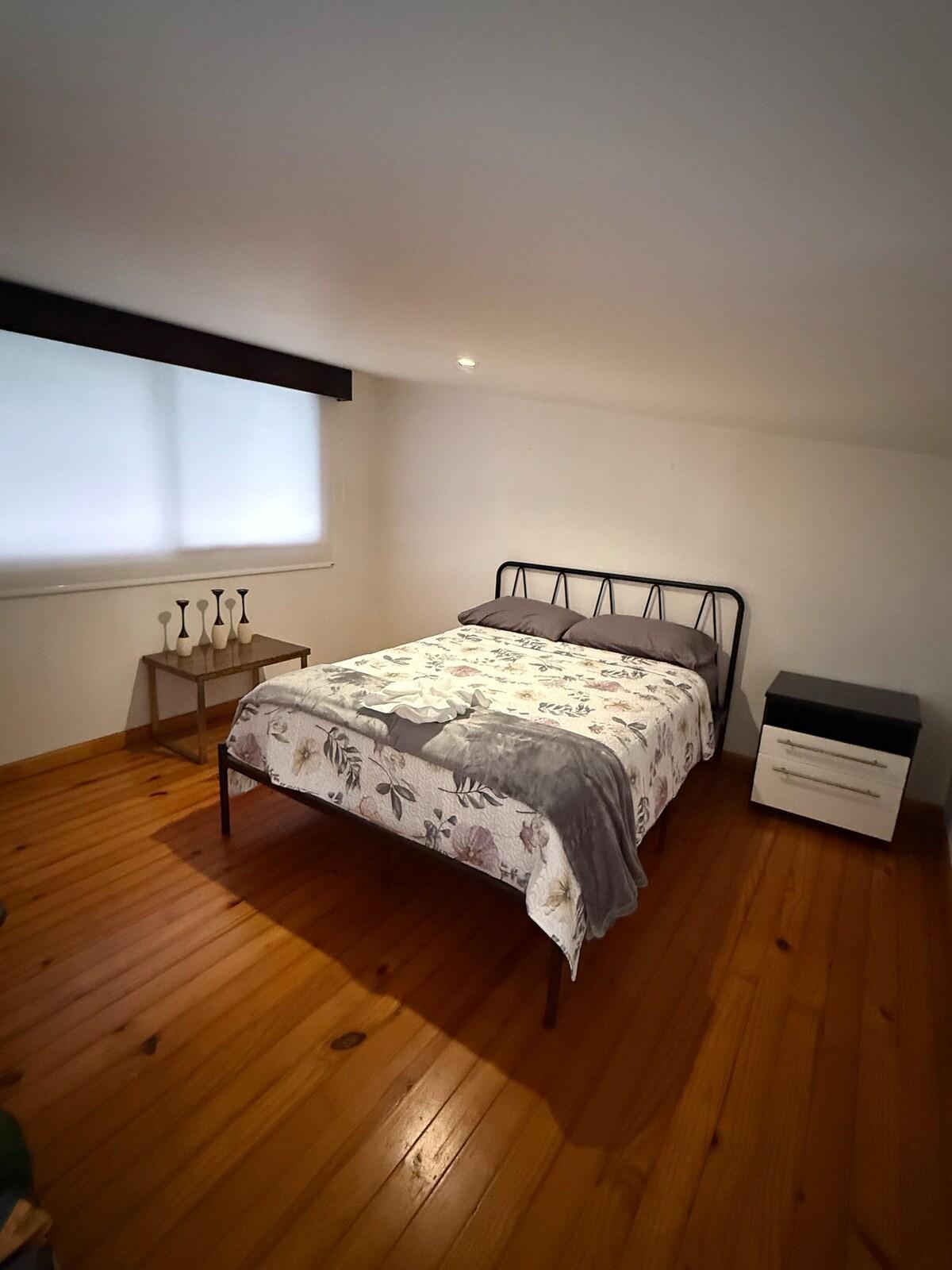 Mezzanine queen bedroom with warm wood floors and a metal bed frame
